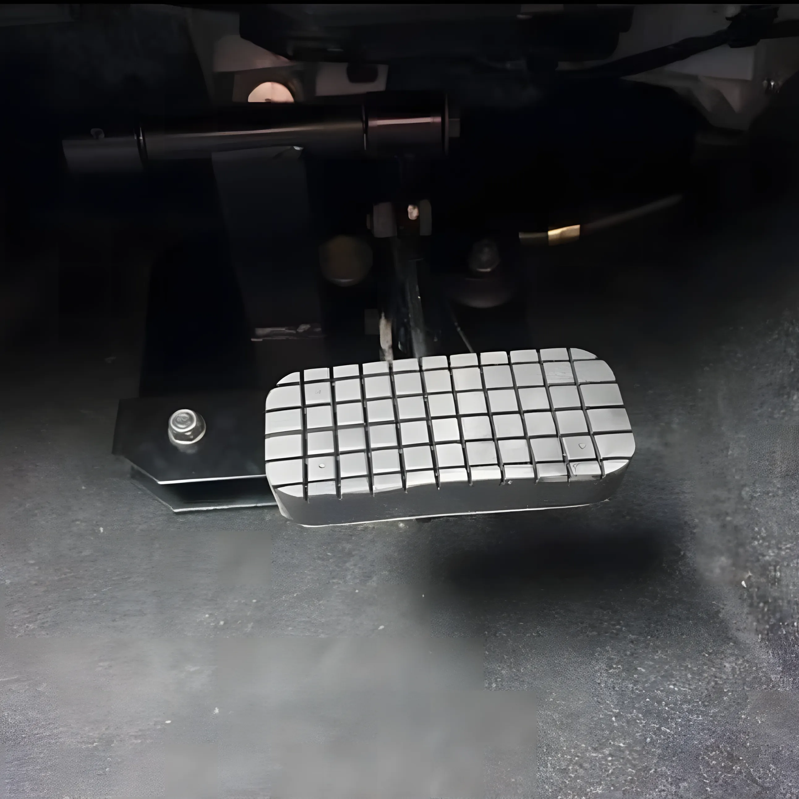 A single brake pedal in a vehicle foot well.