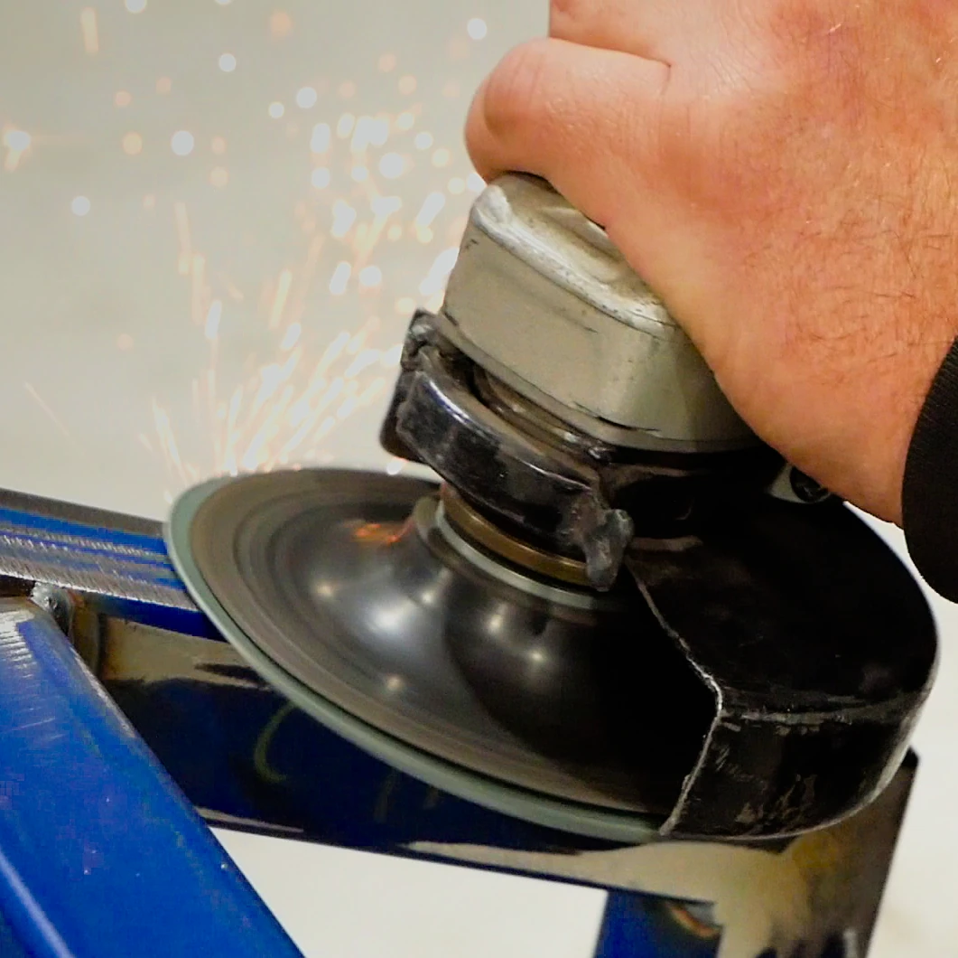 A picture of a handheld angle grinder being used to perfect some metal framing.