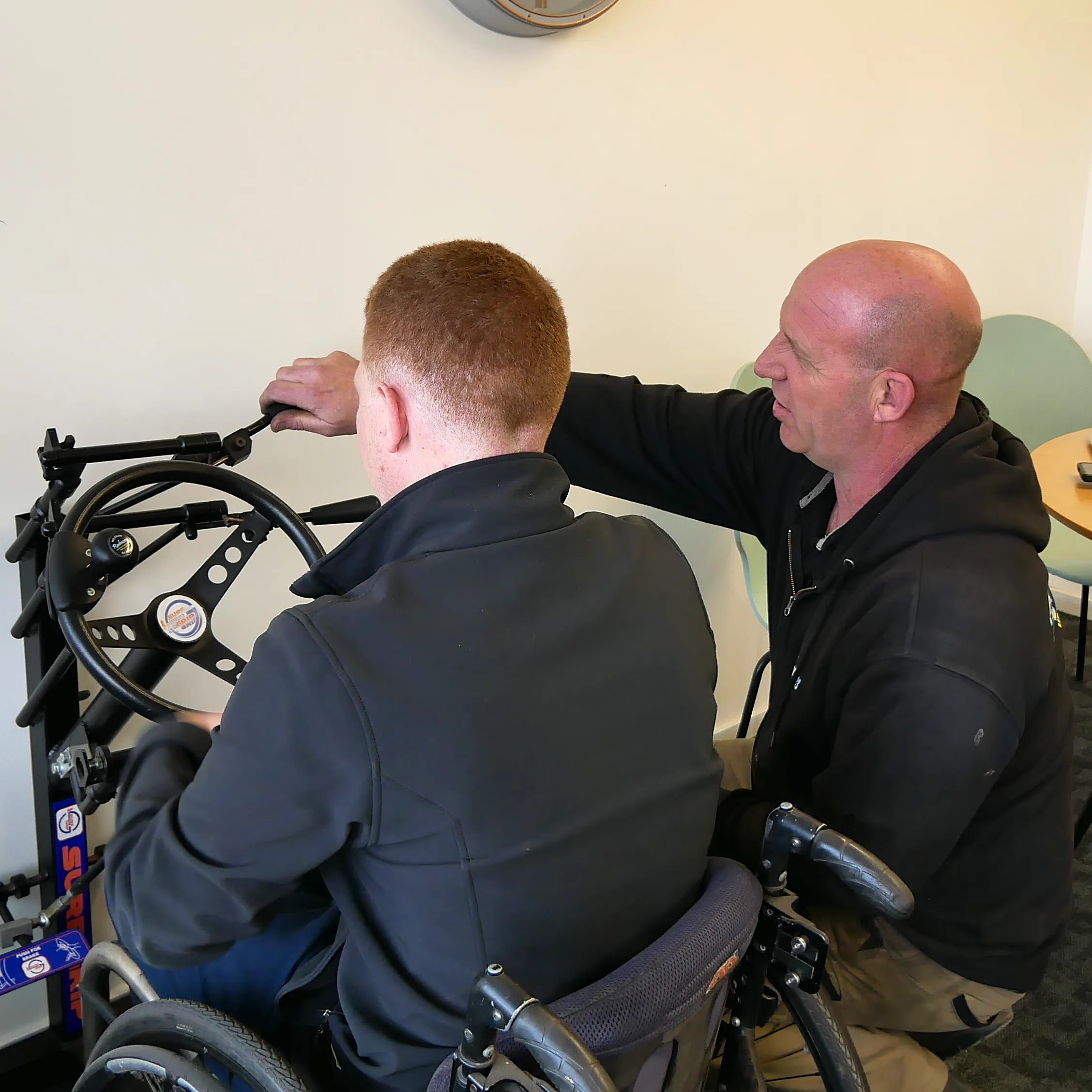 A person seated in a wheelchair looking at hand controls.