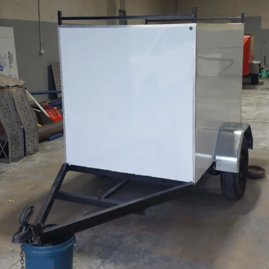 A white, box-shaped, single axle trailer for use with a smaller vehicle.