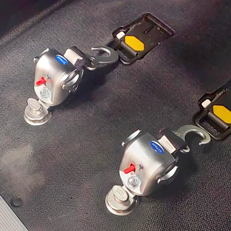 Two vehicle restraint anchors installed on the floor of a car.