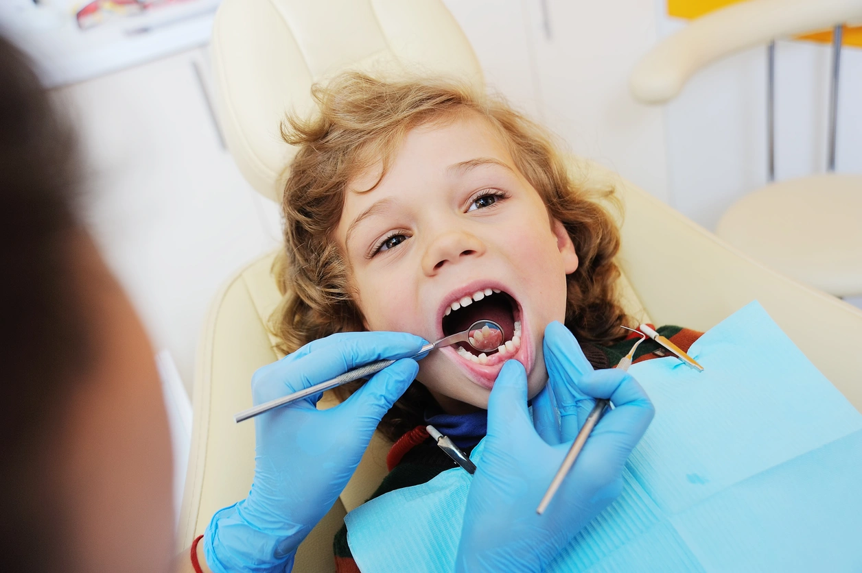 Pediatric dentist examining a child’s teeth during a routine checkup.
