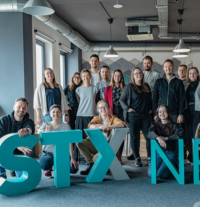 A photo of stx next happy employees with STX Next big logo.