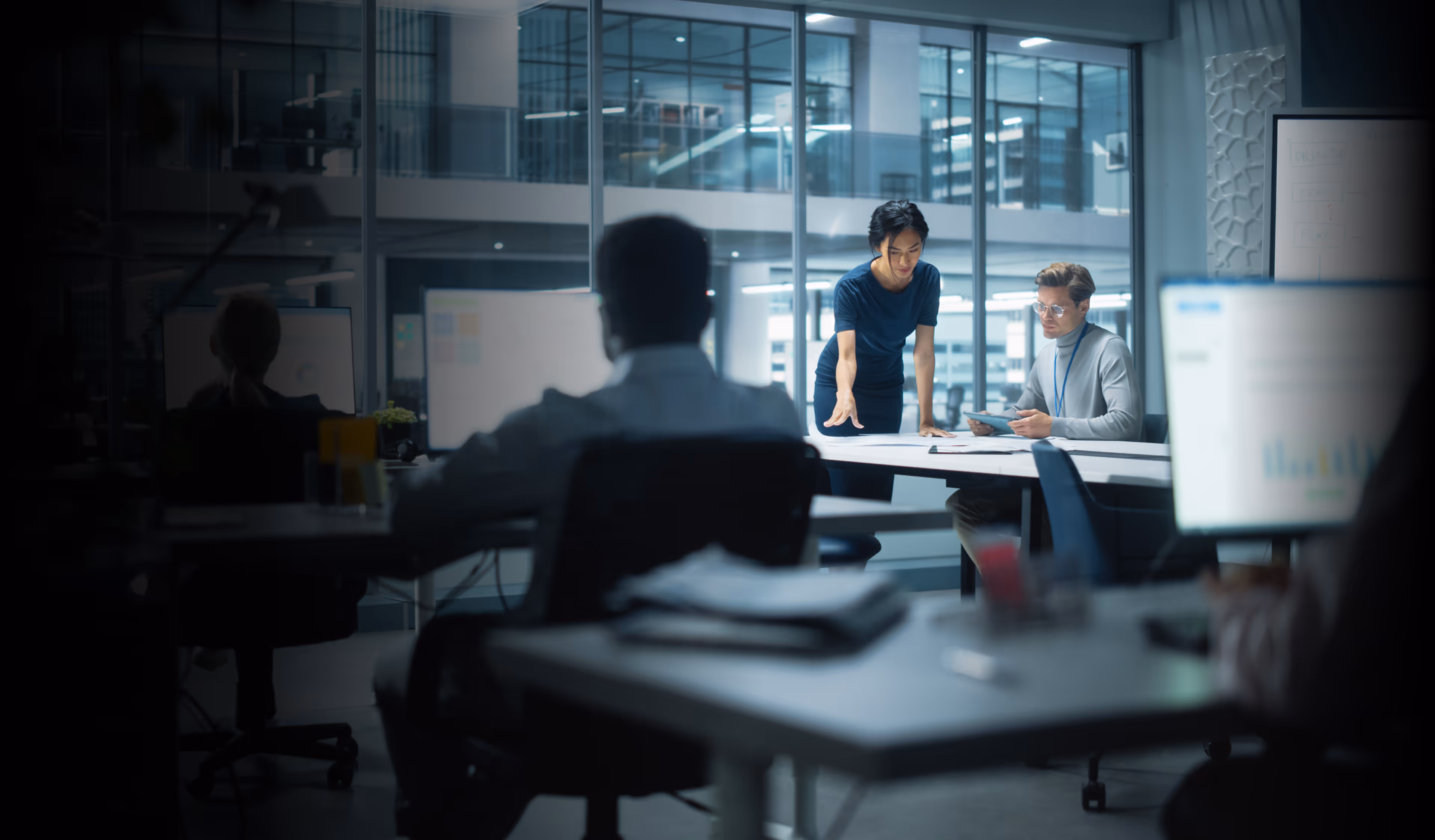 Two professionals collaborating at a table in a modern office with large glass windows.