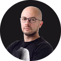 Portrait of a bald man with glasses wearing a black shirt on a dark background.