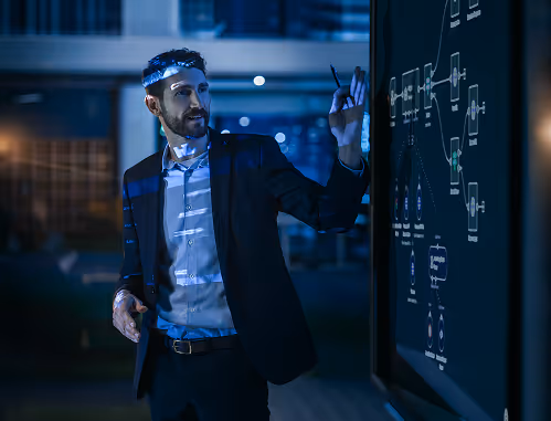 Man in business attire writing a flowchart on a dark board in a dimly lit office.
