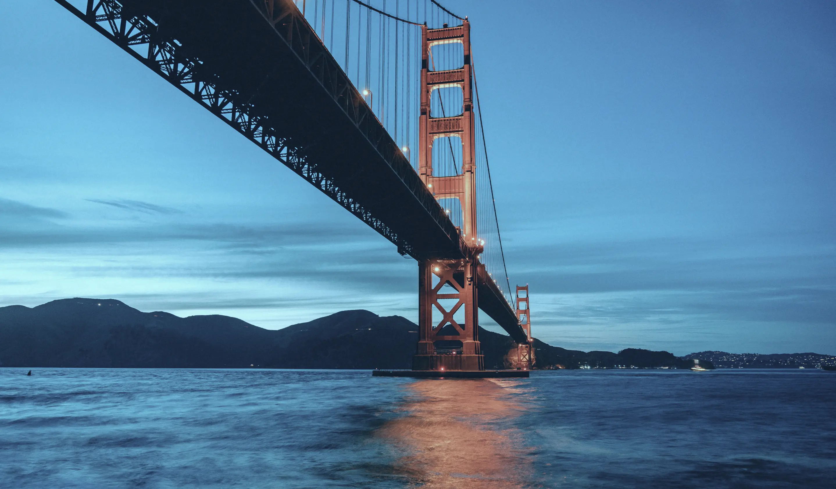 The golden gate bridge is lit up at night.