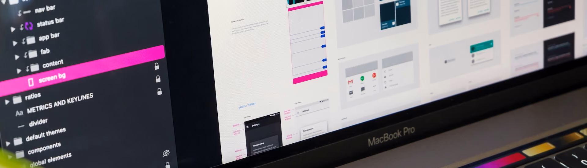 Close-up of a MacBook Pro screen showing a graphic design interface with layers and UI mockups.