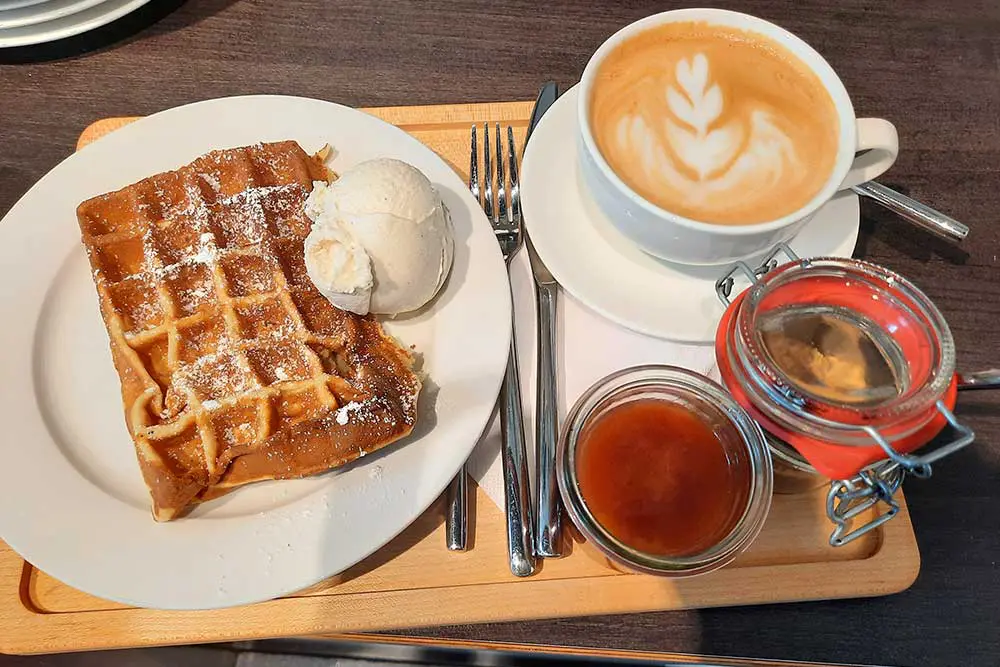 Eis und heiße Waffeln neben einer Tasse Kaffee mit Plätzchen auf Tablett im Café Eisstil in Essen-Holsterhausen 