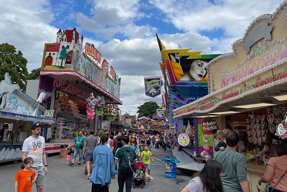 Besucher*innen stehen vorm Riesenrad beim Sommerfest