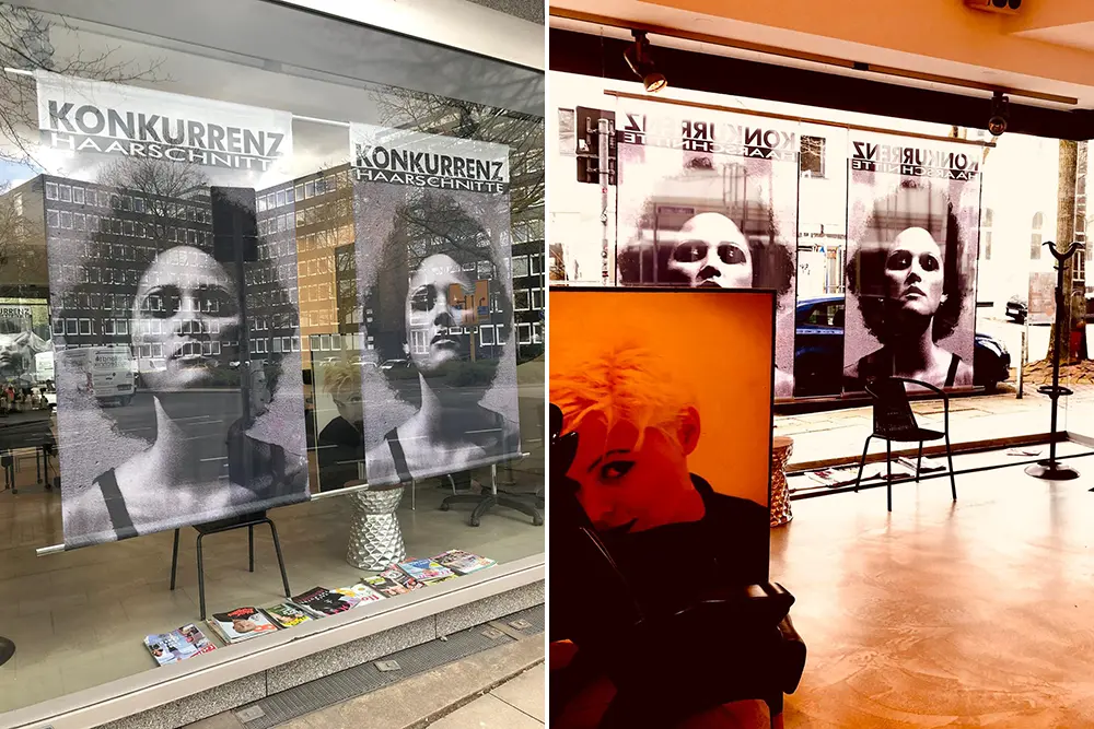 Frau mit toupierten Afro Haar Bob auf Plakat im Schaufenster eines Friseursalons mit grauem Betonboden und minimalistischer Einrichtung im kreativen 00er Look. Die Konkurrenz