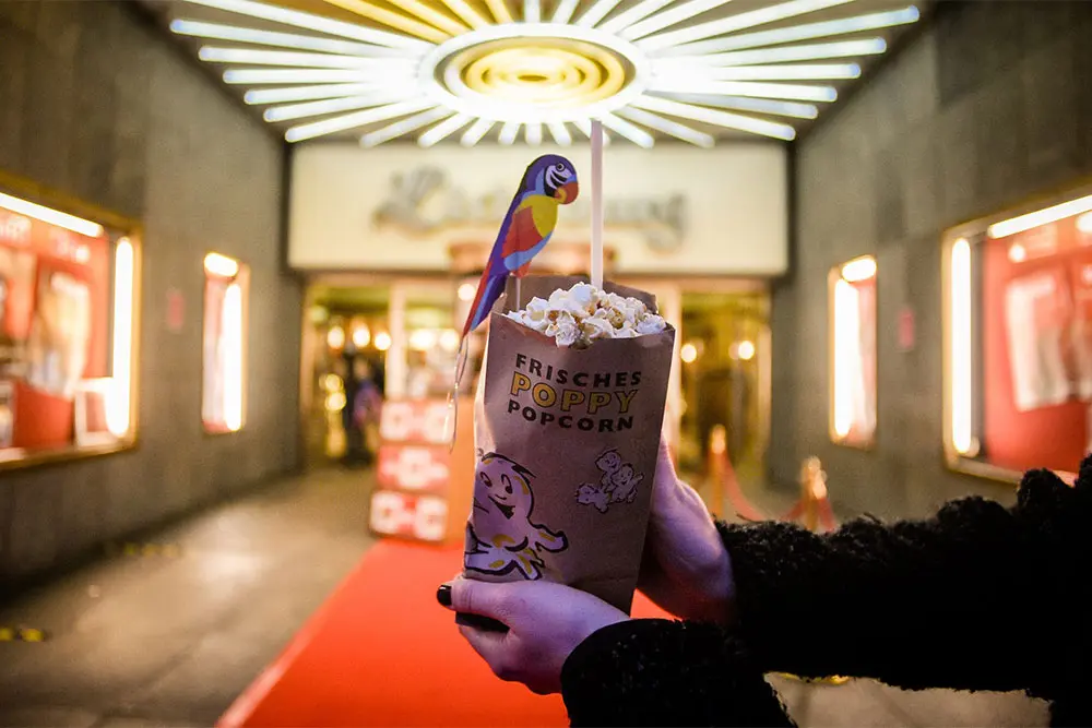 Frau Hand hält Tüte Popcorn vor Deutschlands größtem Filmpalast, die Lichtburg, Essen