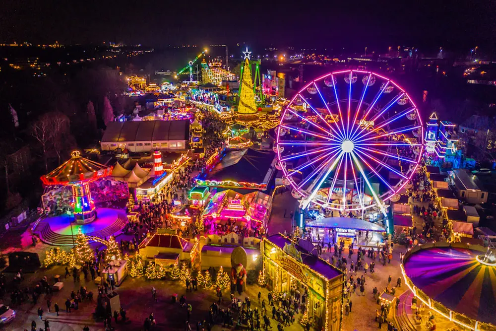 45 Meter hoher mobiler Weihnachtsbaum neben illuminierten Riesenrad vor rasanten Fahrgeschäften, Cranger Weihnachtszauber, Herne, Ruhrgebiet
