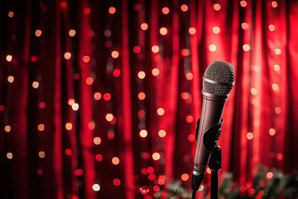 Mikrofon auf der Bühne vor roten Vorhängen und leuchtenden Bokeh-Lichtern