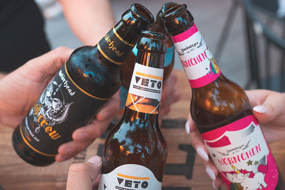 Drei Flaschen Craft Bier und drei Hände 