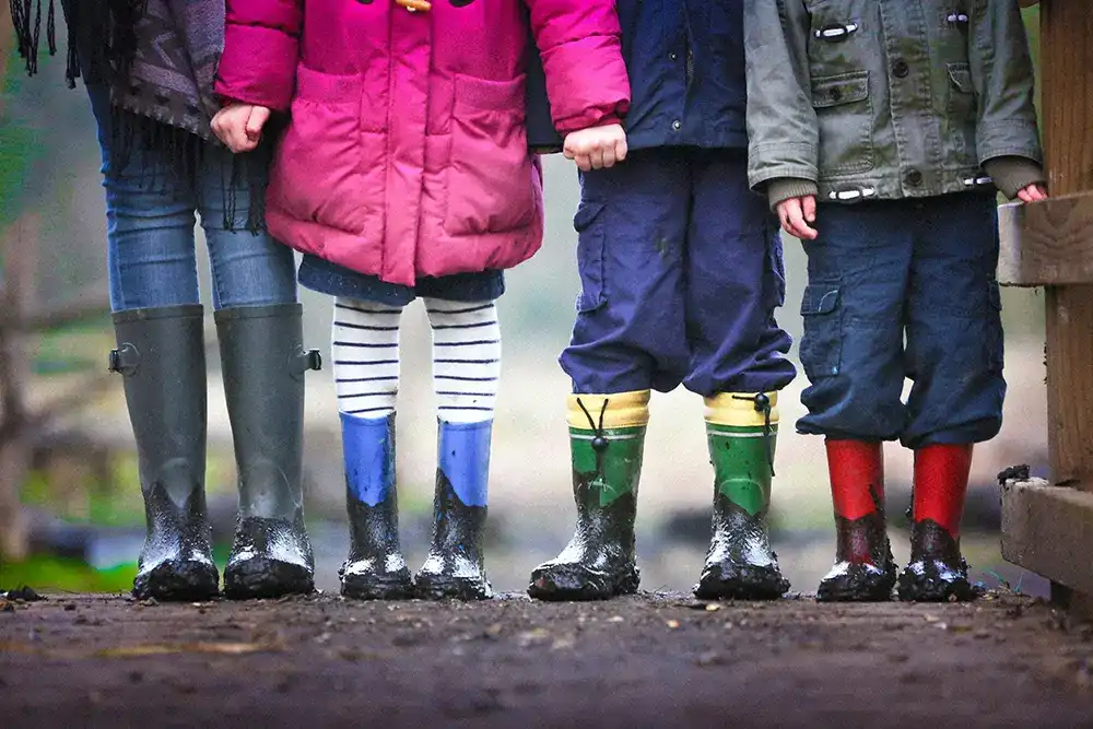Erwachsene neben Kindergruppe in bunten Gummistiefel bilden eine Reihe