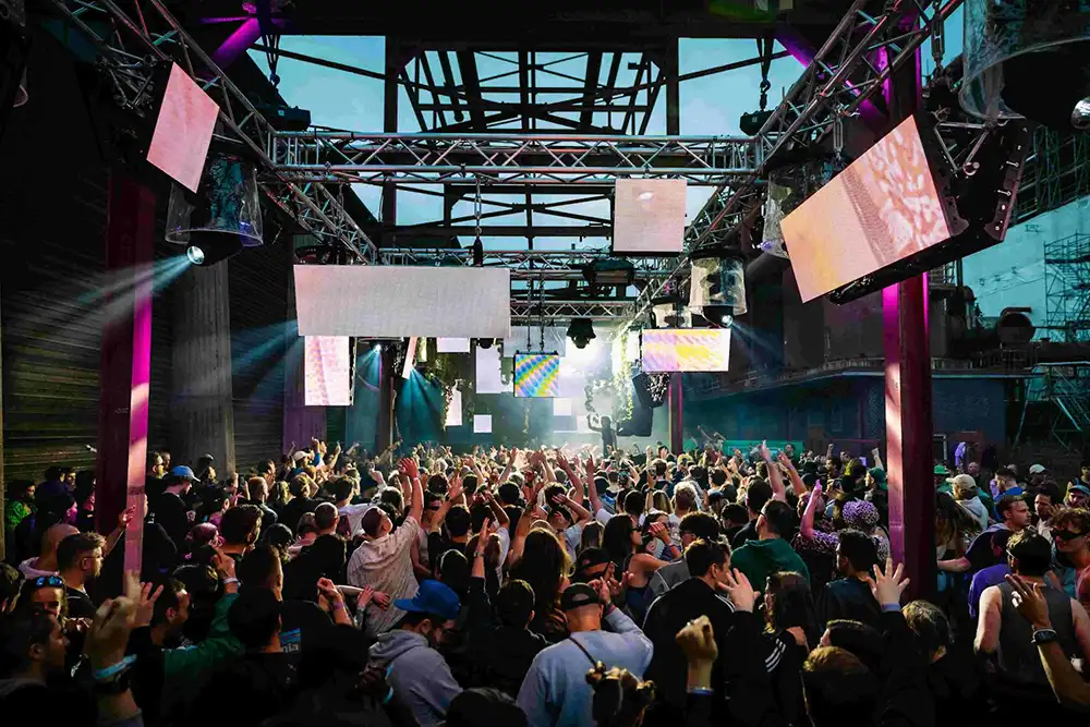Tanzende Festivalbesucher*innen beim Stone Techno Festival in der Industriekulisse auf dem UNESCO-Welterbe Zollverein, Essen