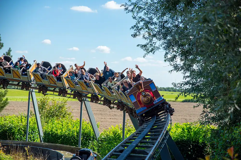 Lachende Menschen mit erhobenen Armen in der Wilden Maus Achterbahn vor blauem Himmel im Wunderland Kalka, RUHR.TOPCARD