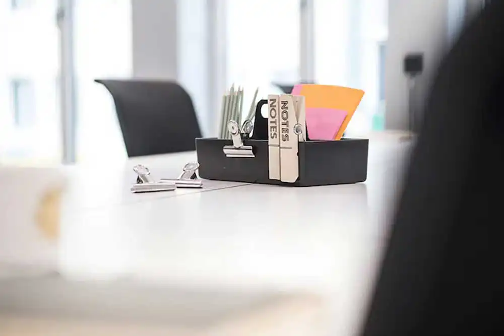 Moderner Arbeitsplatz mit Büroklammern, Haftnotizen und Notizbüchern in einer schwarzen Box im Büro