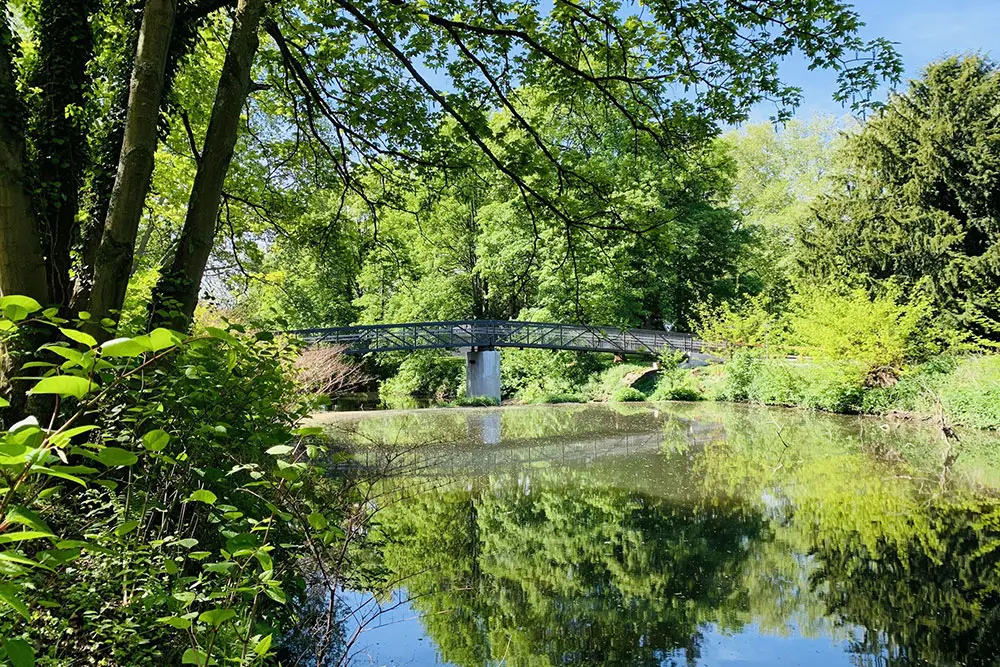 Idyllischer Picknickplatz am Wasser auf der Brehminsel in Essen-Werden mit Blick auf die Fußgängerbrücke.