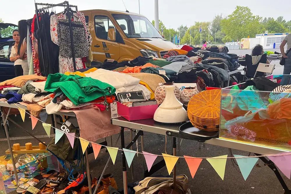 Dicht gedrängte Kleiderstangen und stöbernde Besucherinnen auf dem Outdoor-Mädelsflohmarkt an der Metro in Essen.