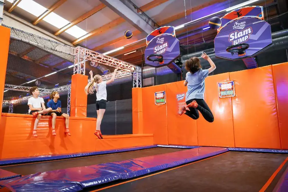 Kinder und Jugendliche powern sich beim Basketball auf Trampolinen im JUMP House Essen aus als wetterunabhängiger Ausflugstipp in den Sommerferien.