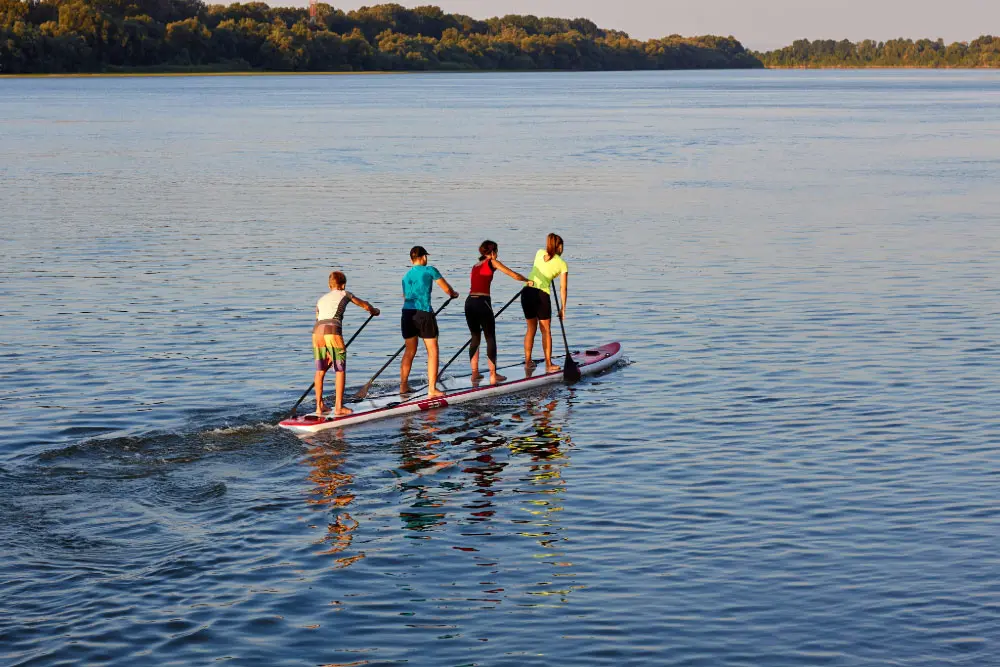 Vier Personen paddeln gemeinsam auf einem riesigen Tandem-SUP-Board bei der ehemals in Essen ansässigen und nun in den Harz umgezogenen SUP Schule ORIGINAL-sein.