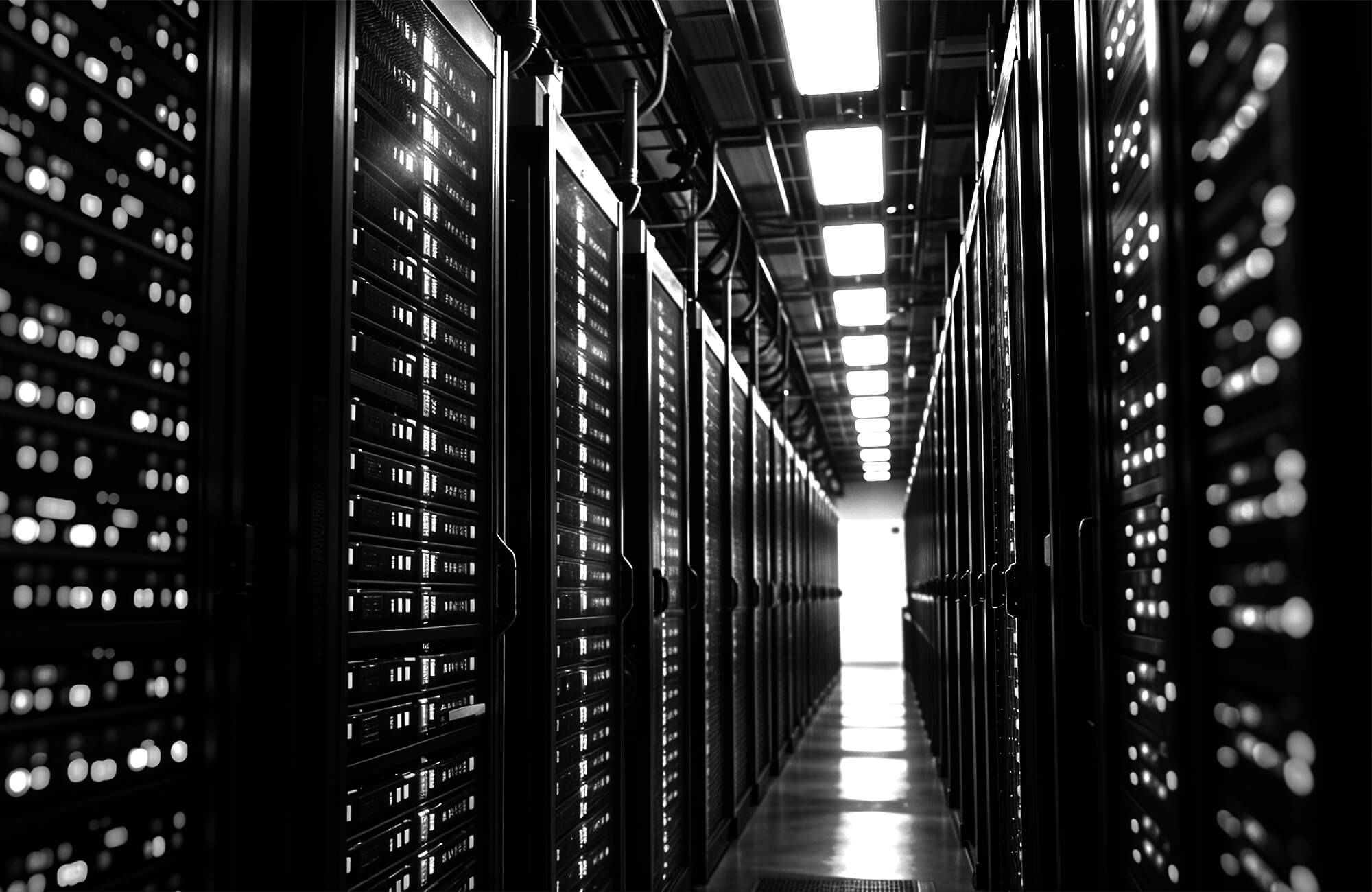 Photo of a long aisle with rows of lit server racks in a data center.