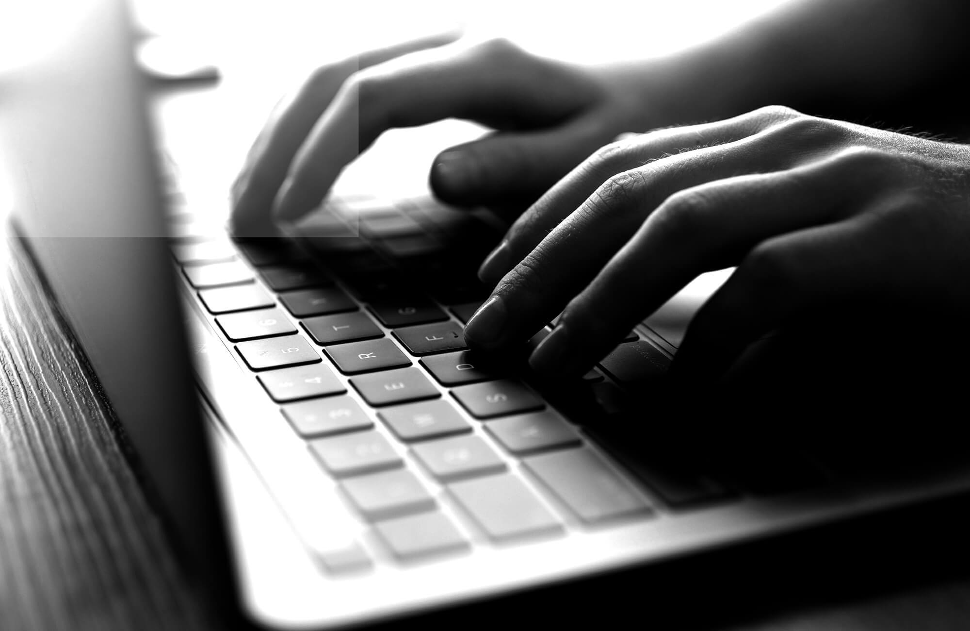 Close-up of hands typing on a laptop keyboard..