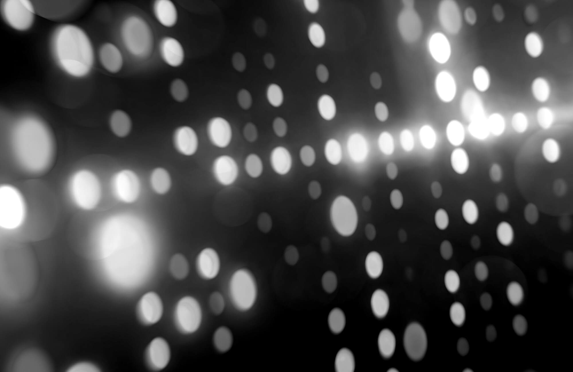 Abstract grayscale image with scattered, blurred circular light spots creating a bokeh effect.