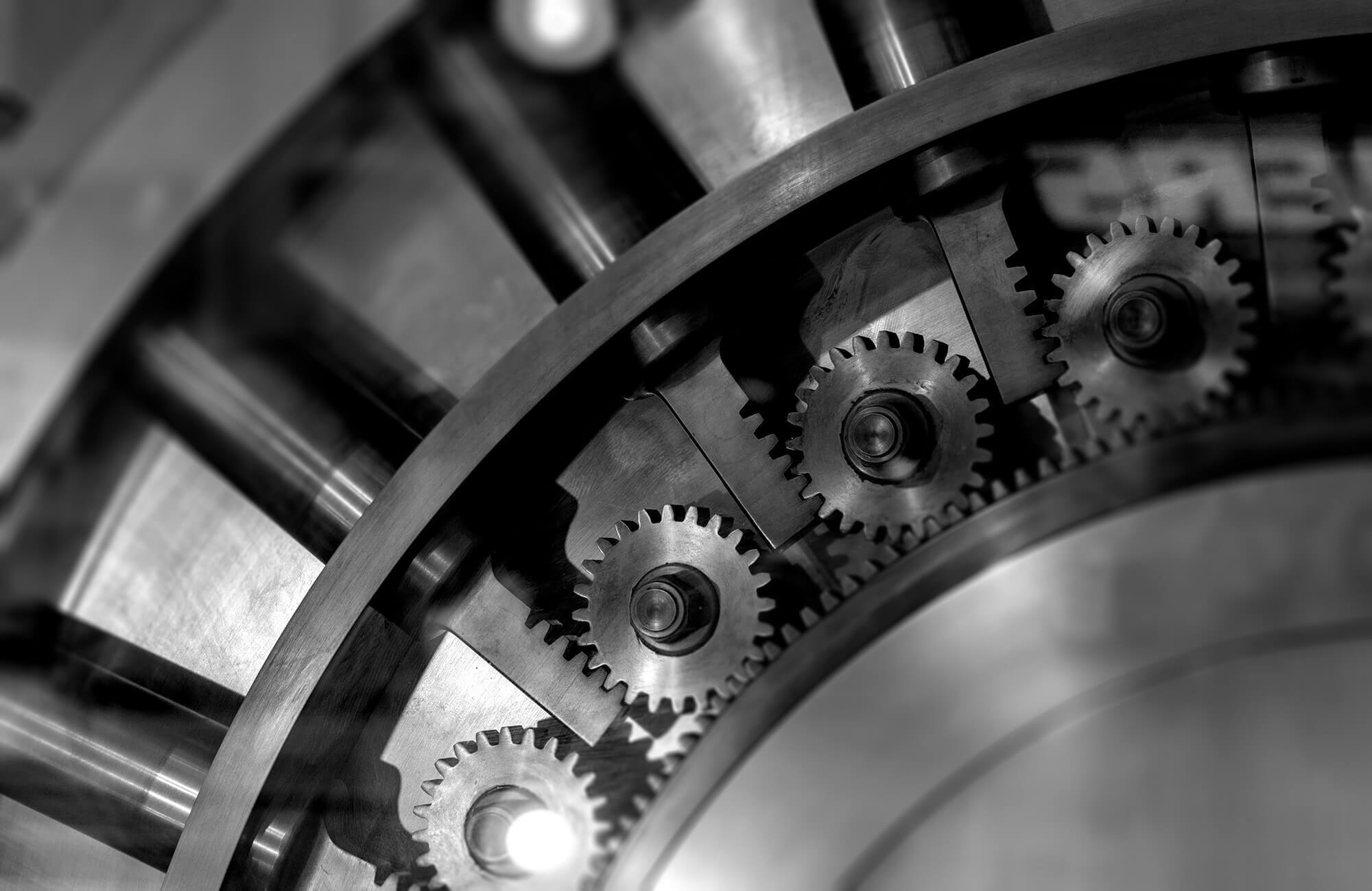 Close-up of interlocking metal gears inside a large secure vault.