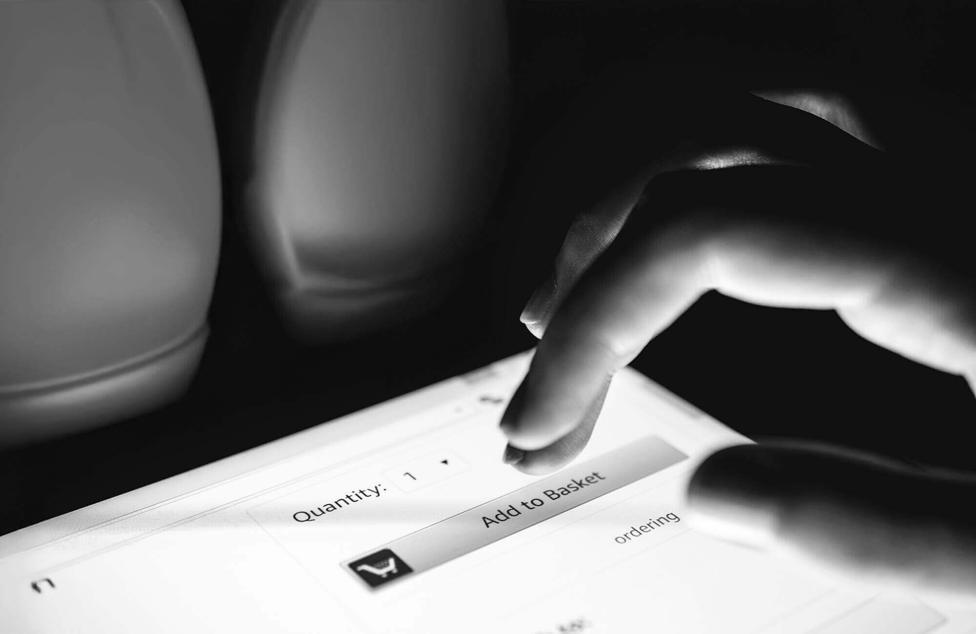 Close-up of a hand about to click an 'Add to Basket' button on a digital shopping interface.