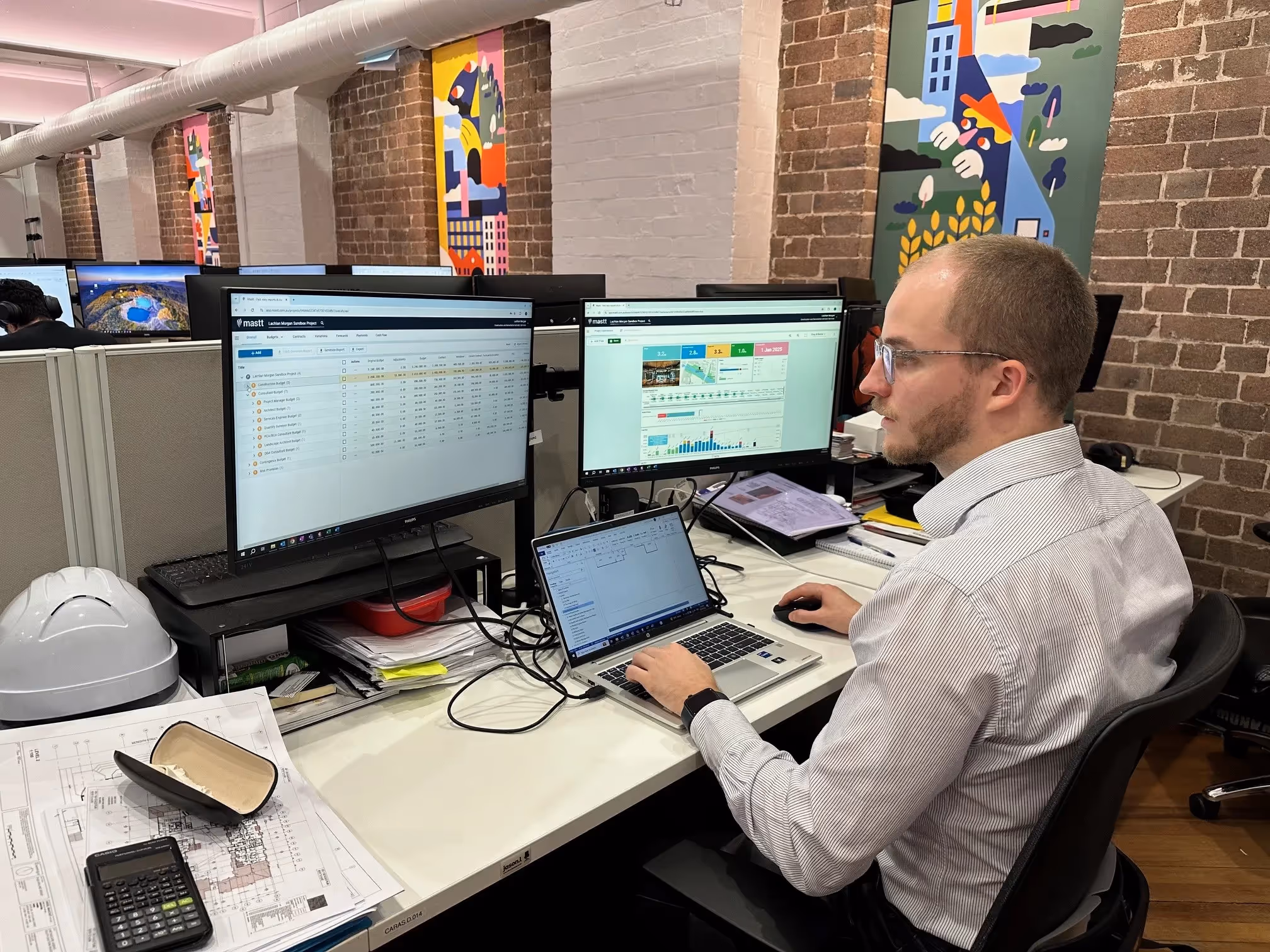 Lachlan from CARAS observing a Mastt Dashboard report & financial ledger.