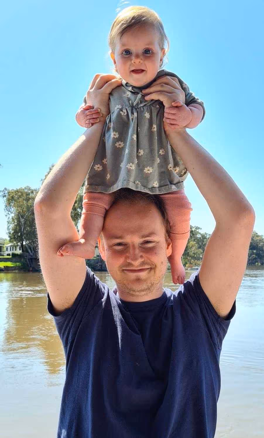 A man holding his baby girl above his head