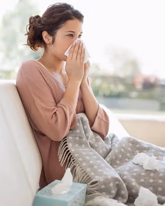 How to Call in Sick as a Project Manager: A photo of a project manager wiping her nose with a tissue.