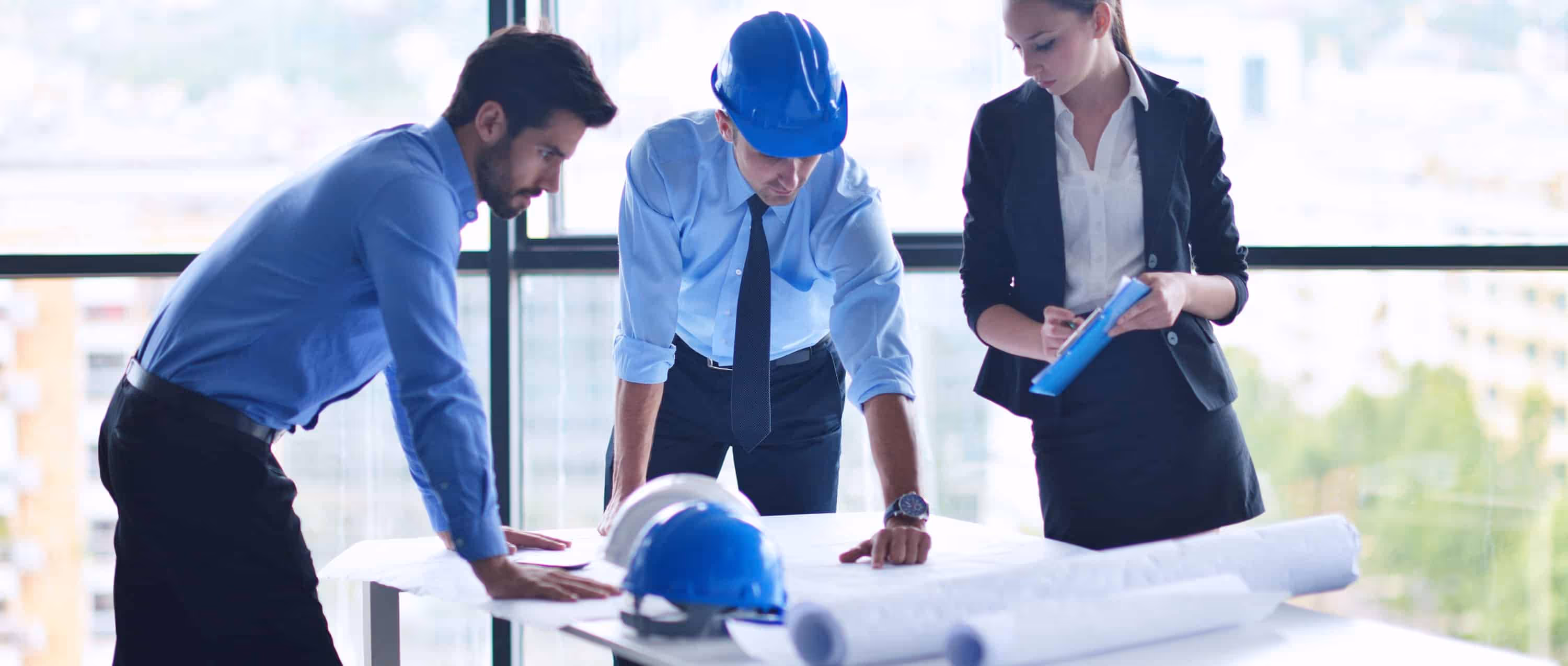 Project Manager vs Program Managers: Differences and Interdependencies: a photo of 3 professionals discussing over a project.