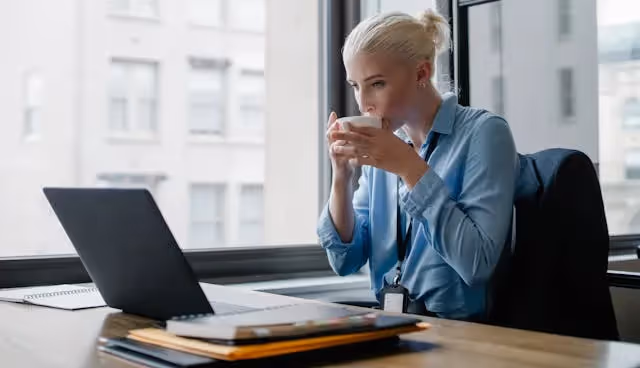 3 AIPM Memberships to Elevate Your PM Career: a photo of a woman drinking in a cup looking at the laptop.