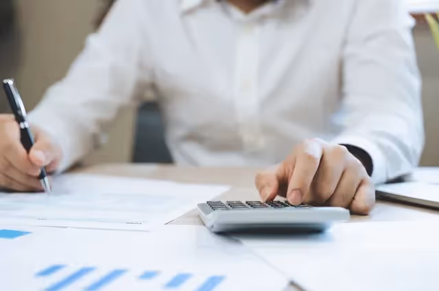 What is a Superintendent? 5 Key Roles of a Construction Project Superintendent: an image of a person writing while the other hand is using a calculator.