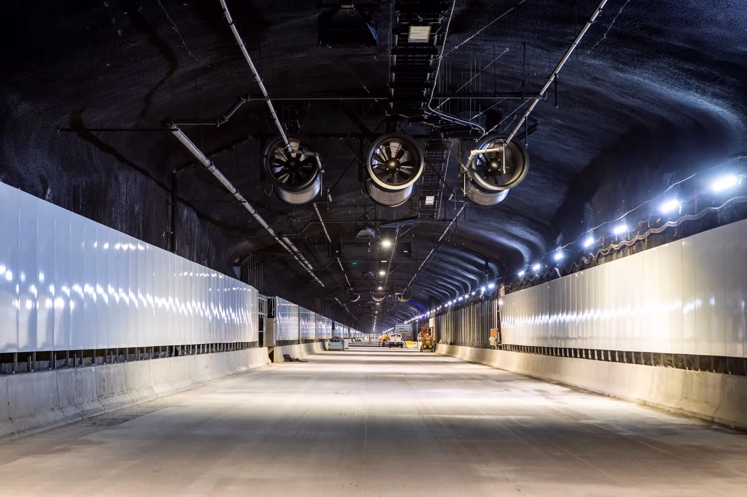 Interior of a modern tunnel with lighting and ventilation systems under construction.
