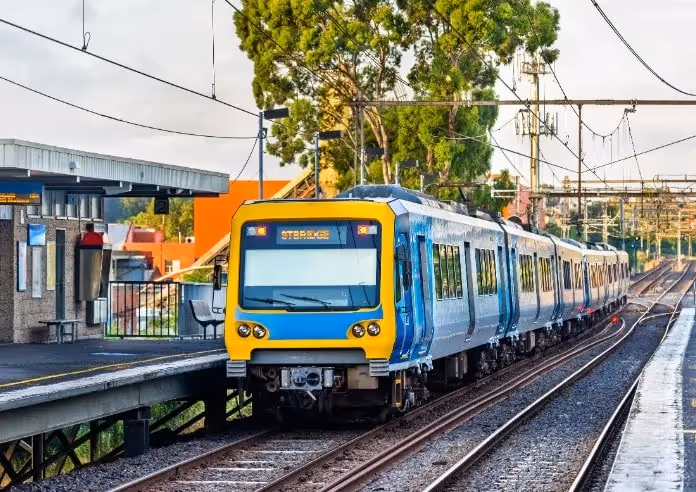 A modern blue and yellow metro train at an Australian suburban station.
