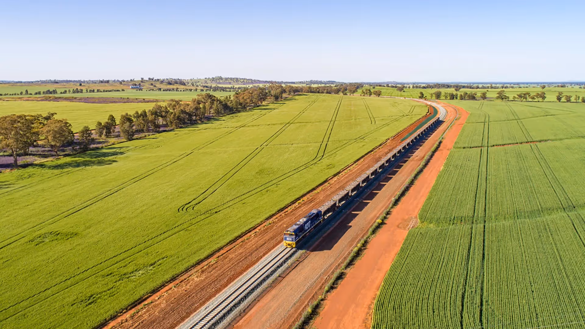 Aerial view of the Inland Rail project running through green farmland in Australia.