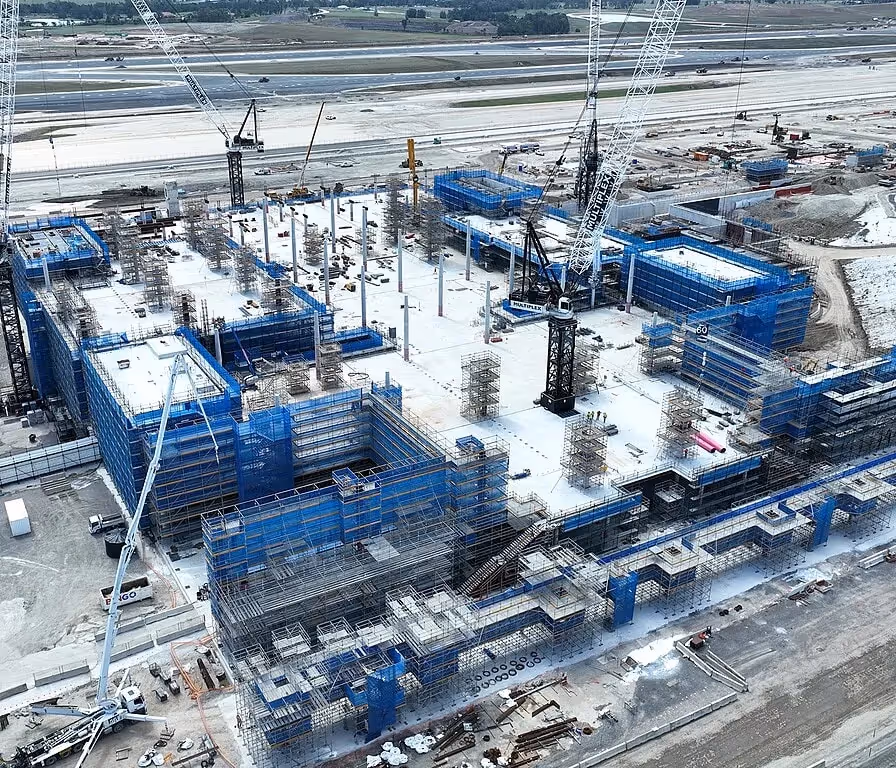 Aerial view of large-scale construction work on an infrastructure project with cranes and scaffolding.