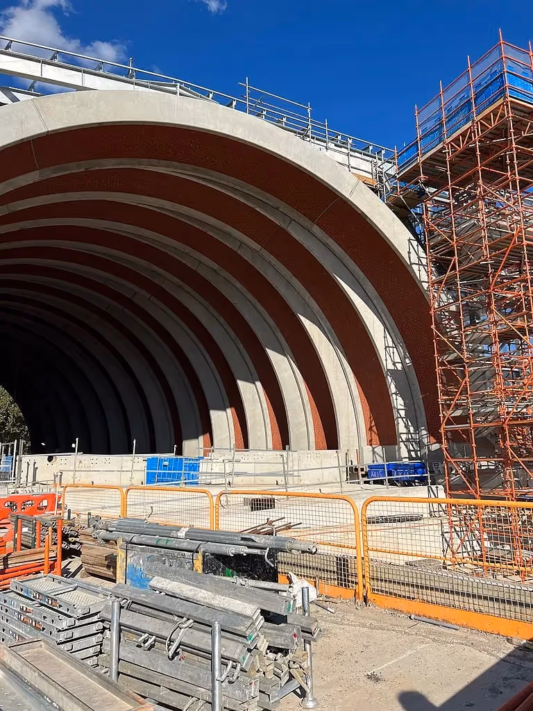 Construction of a large curved infrastructure project with scaffolding and materials.