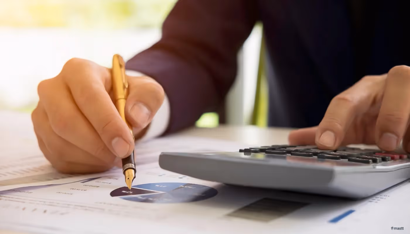 Close-up of a person analysing financial charts and using a calculator for budgeting.