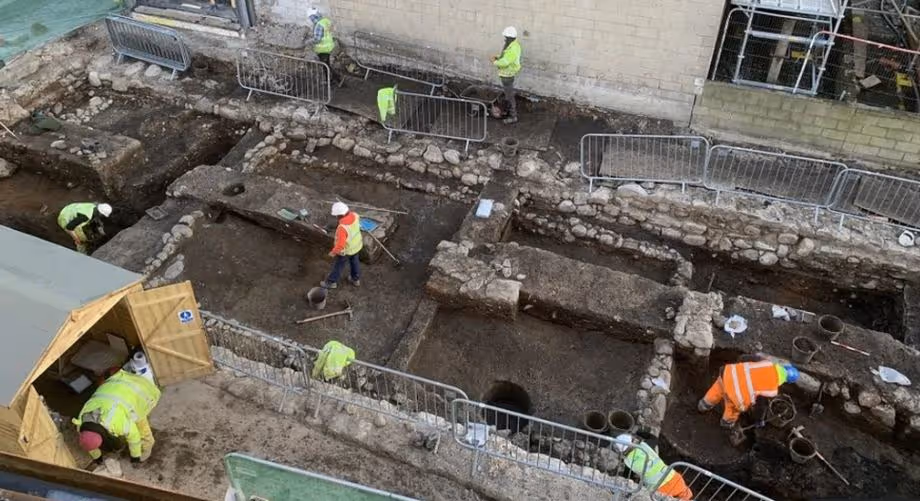 Construction workers uncover unexpected underground structures at an excavation site, revealing latent conditions.