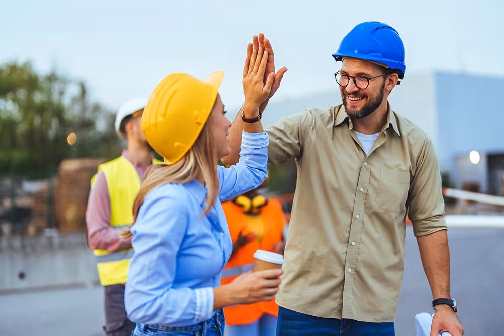 Construction professionals celebrating successful forecast project management on-site.