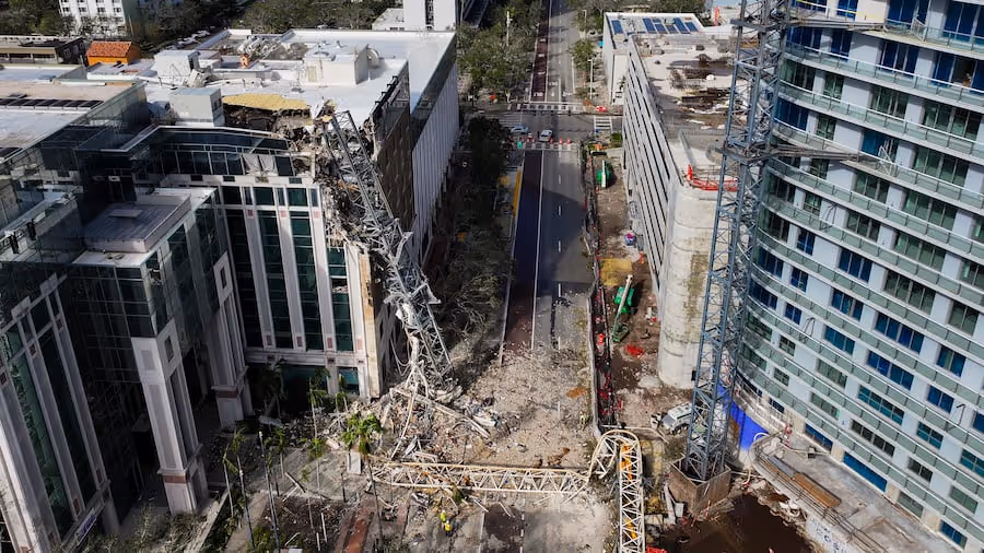 Aerial view of a collapsed crane embedded in an office building at 490 First Ave. S, St. Petersburg, with the crane’s frame extending across the street amid rubble and surrounding high-rises.