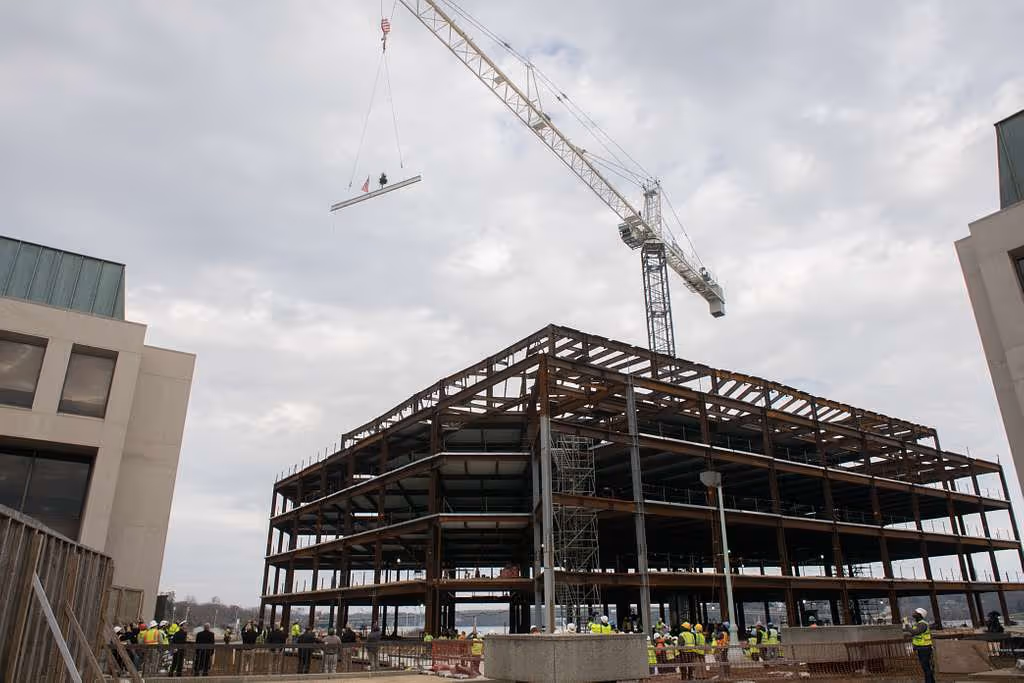 Beam lifted by crane during topping out ceremony at construction site