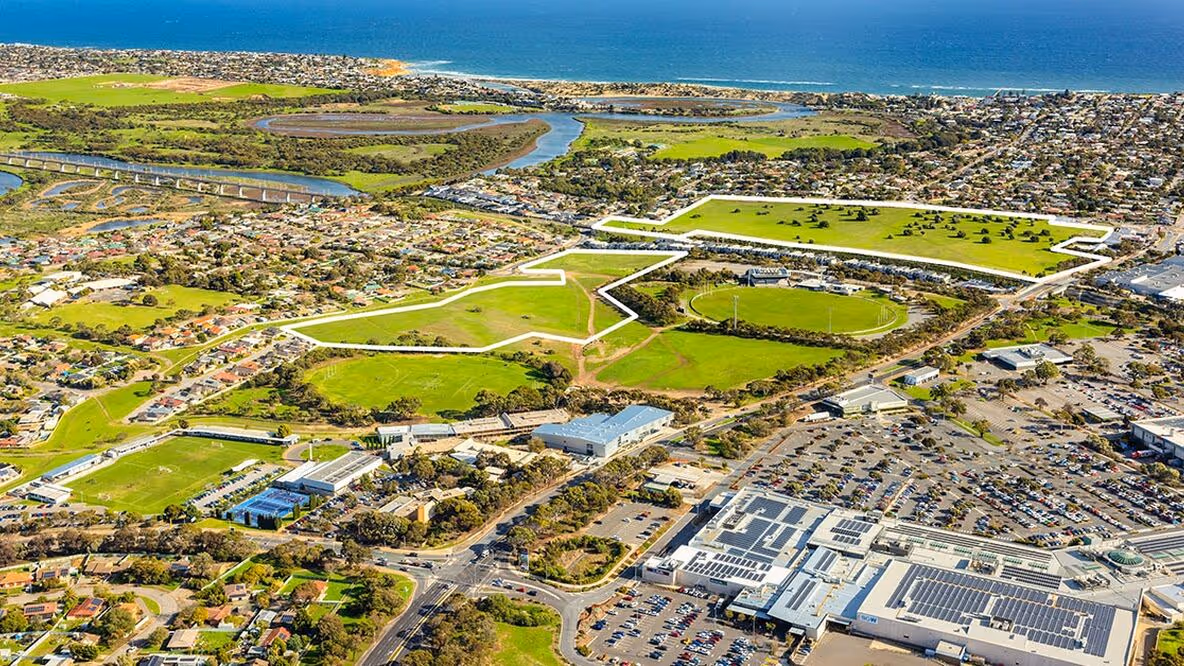 Aerial photograph of Noarlunga Downs Housing Estate in South Australia showing open green spaces, residential zones, commercial areas, and surrounding coastal landscape.