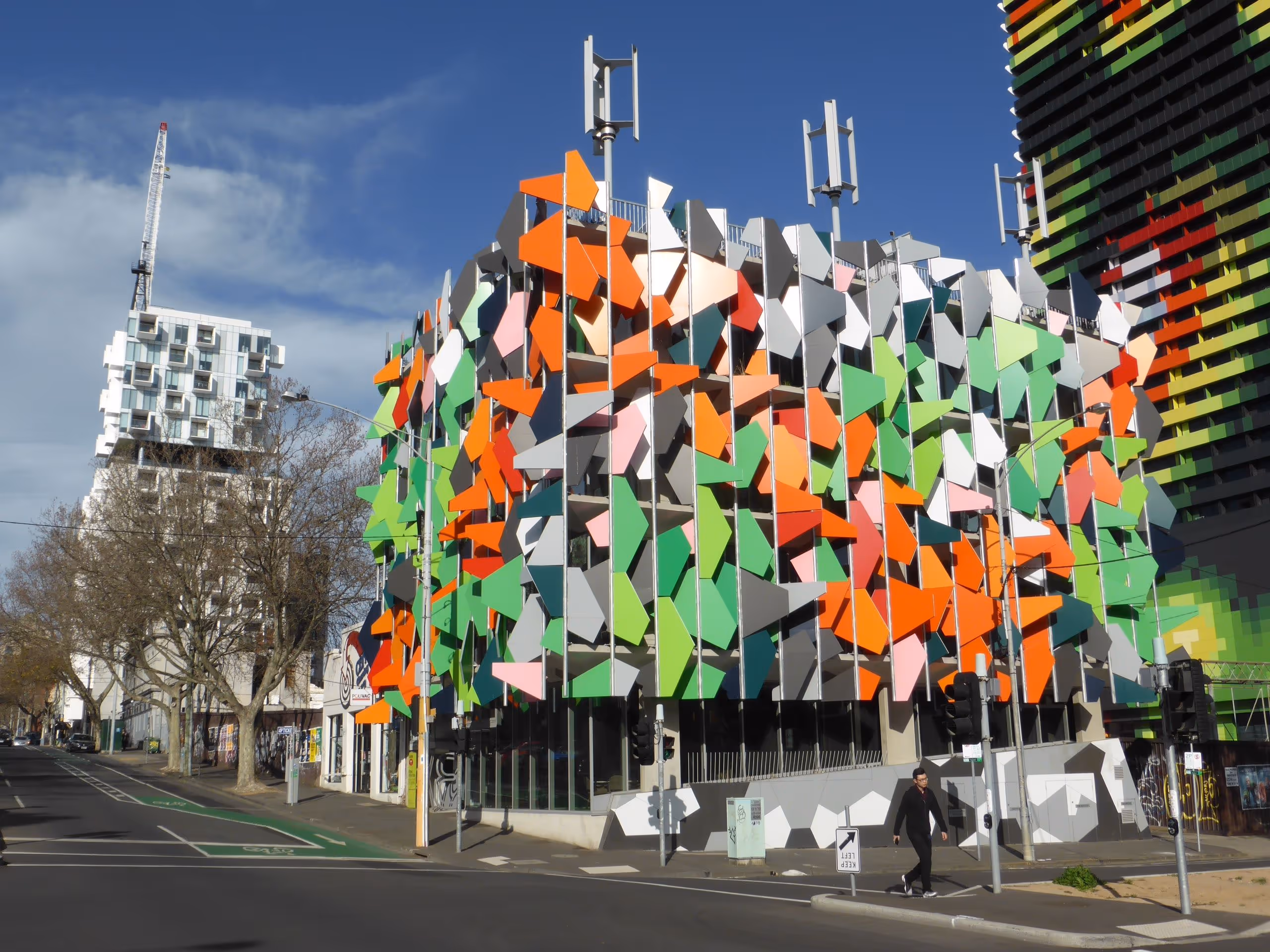 Colorful Pixel Building in Melbourne featuring a patterned green-red façade and rooftop wind turbines, designed for energy-efficient office use.